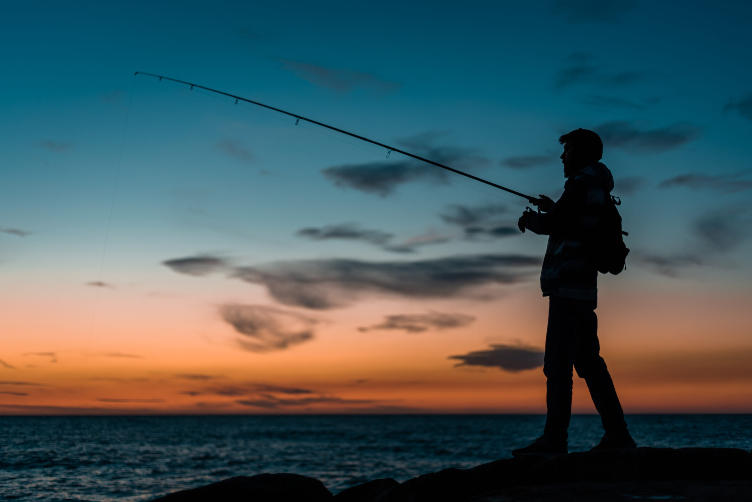 silueta-hombre-pescando-playa-al-atardecer